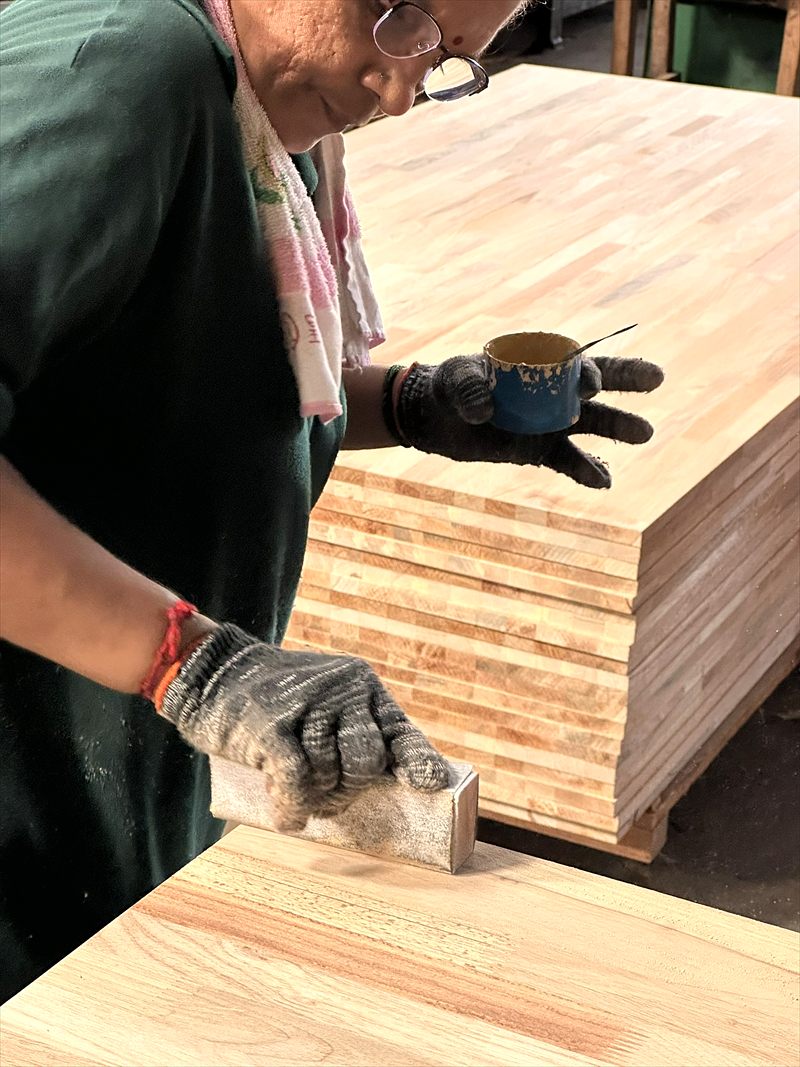 Hand-finishing a finger-jointed laminated board on the production floor